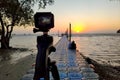 Camera mounted on a tripod shooting a coupe on the pier and sunrise under the sea. Focus on the camera Royalty Free Stock Photo