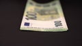 Camera is moving dolly in towards European 100 hundred EURO money banknotes on black background.