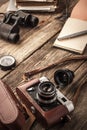 Camera with notebook and binoculars on the wooden table vertical Royalty Free Stock Photo