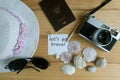 Camera, passport, sunglasses, hat, shells and message let`s go travel on wooden floor Royalty Free Stock Photo