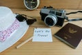 Camera, passport, sunglasses, hat, shells and message let`s go travel on wooden floor Royalty Free Stock Photo