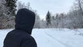 Camera pursues the man who walks on the winter road in the daytime.