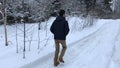 Camera pursues the man who walks on the winter road in the daytime.