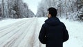 Camera pursues the man who walks on the winter road in the daytime.