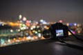 Camera put on rooftop edge with bokeh night city background Royalty Free Stock Photo