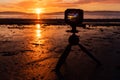 A camera recording a timelapse of the sunset on the beach Royalty Free Stock Photo