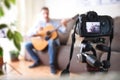 Camera recording video blogger doing review of guitar at home