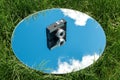camera and sky reflection in round mirror on grass Royalty Free Stock Photo