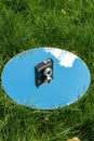 camera and sky reflection in round mirror on grass Royalty Free Stock Photo
