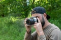 The camera smokes in the hands of photographer takes a photo in nature. young bearded man photographs outdoors