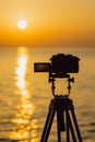The camera stands on a tripod and capture the sunset.