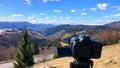 The camera takes a view of the mountains timelapse over the forest on a tripod.