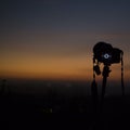 Camera on a tripod with golden horizon at dusk