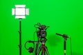 The camera on the tripod, led floodlight, headphones and a directional microphone on a green background. The chroma key Royalty Free Stock Photo