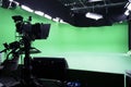 The camera on the tripod, led floodlight, prompter and a monitor on a green background.