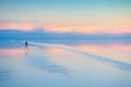 Camera with tripod shooting sunset on Salar De Uyuni salt flat in Bolivia