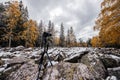 Camera on a tripod shoots an autumn forest covered with snow