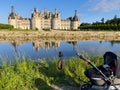 Camera on Tripod and Stroller Capturing Chambord Castle\'s Reflection in the Cosson River Royalty Free Stock Photo