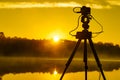 Camera on tripod take photo from sunrise over lake Royalty Free Stock Photo