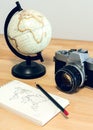 Camera, world globe and notebook with world map on a wooden desk. Travel concept image: planning a journey Royalty Free Stock Photo