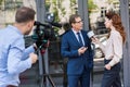 cameraman and news reporter with microphone interviewing businessman near office Royalty Free Stock Photo