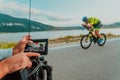 A cameraman with professional equipment and camera stabilization films a triathlete on the move riding a bicycle