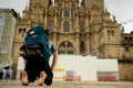 Camino de santiago pilgrim kneeling in front of santiago cathedral after finish the pilgrimage, praying bare feet in plaza del