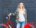 Camo Utility Overcoat. A beautiful girl in a fashionable outfit posing with a trendy vintage red bicycle on the street Royalty Free Stock Photo