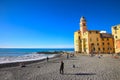 Camogli, Italy - People relaxing on the beach and the basilica Santa Maria Assunta in the background