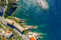 Camogli rocky coast aerial view. Boats and yachts moored near harbor with green water and lighthouse.