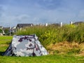 Camouflage tent in a field by house estate, concept homeless, Rich and poor