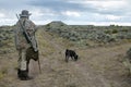 Camouflaged hunter with rifle and tracking dog