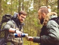 Camp, adventure, traveling and friendship concept. Man with a backpack and beard and his friend hiking in forest.