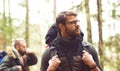 Camp, adventure, traveling and friendship concept. Man with a backpack and beard and his friend hiking in forest.