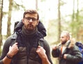 Camp, adventure, traveling and friendship concept. Man with a backpack and beard and his friend hiking in forest.