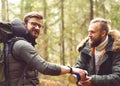 Camp, adventure, traveling and friendship concept. Man with a backpack and beard and his friend hiking in forest.