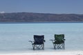 the camp chairs are alone at the lake