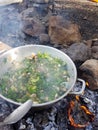 Camp cooking in the field on open fire - a big pan with vegtables and edible wild plants Royalty Free Stock Photo