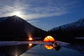 Camp near the mountain lake. Night landscape with a tent near the water. Royalty Free Stock Photo