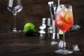 Campari tonic alcohol cocktail with red bitter, tonic, lime and ice. Old wooden table background, bar tools, selective focus. Copy