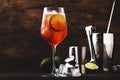 Campari tonic alcoholic cocktail with red bitter, tonic, lime and ice. Old wooden table background, bar tools, selective focus. Royalty Free Stock Photo