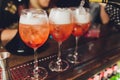 Campari tonic alcoholic cocktail with red bitter, tonic, lime and ice. Old wooden table background, bar tools, selective