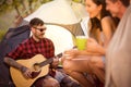 Camper man in the company of his friends plays guitar Royalty Free Stock Photo