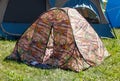 A camper tent with a camouflage pattern is sitting in a grassy field Royalty Free Stock Photo