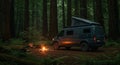 Camper van parked in a dense forest with towering trees, likely conifers. A campfire Royalty Free Stock Photo