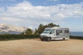 Camper Van trailer parking on beautiful place on background of blue Mediterranean sea and mountain view.