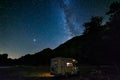 Camper van under panoramic night sky in the Alps. The Milky Way galaxy arc and stars over illuminated motorhome. Camping freedom Royalty Free Stock Photo