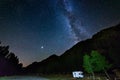 Camper van under panoramic night sky in the Alps. The Milky Way galaxy arc and stars over illuminated motorhome. Camping freedom Royalty Free Stock Photo