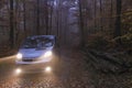 Camper van in wonderful autumn forest with fall foliage leaves on the road.Road trip and travel freedom concept, tourism in RV