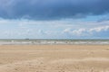 Camperduin beach with the sea with small waves with foam and a fishing boat in the background Royalty Free Stock Photo